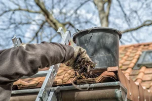 man on ladder cleaning gutters